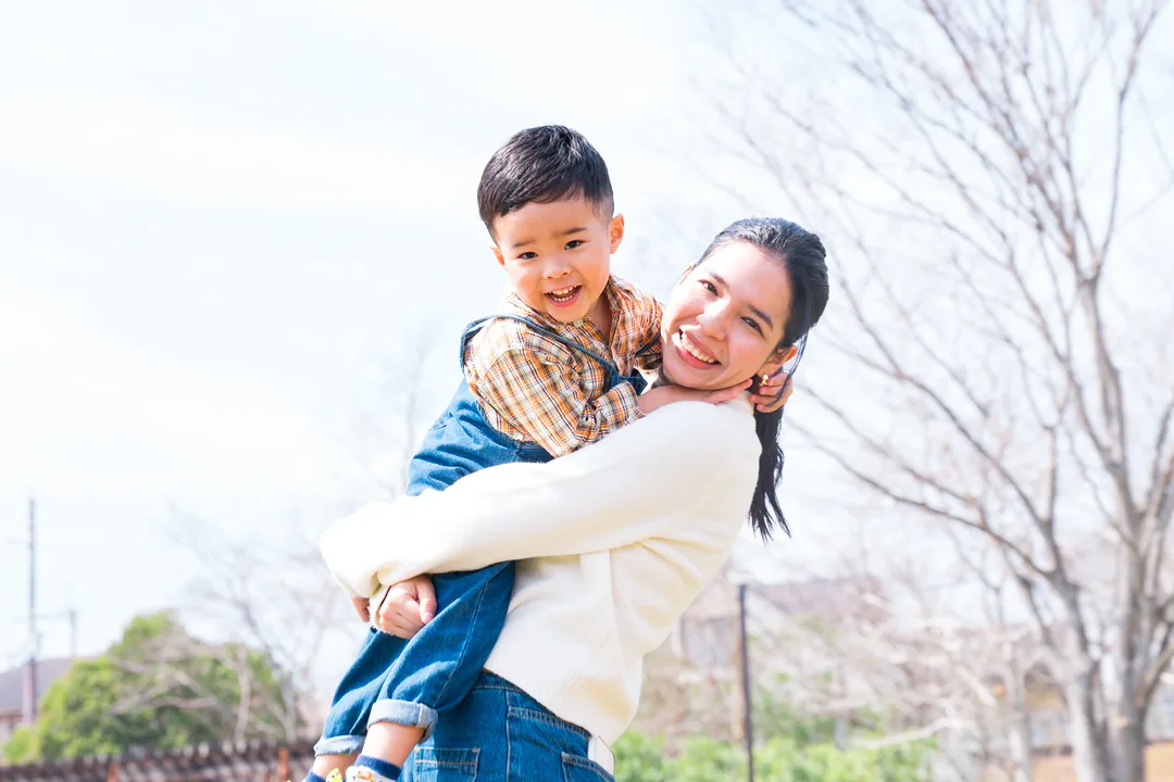子どもを抱き、笑顔を見せる講師のみる